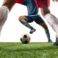 Fighting. Close up legs of professional soccer, football players fighting for ball on field isolated on white background. Concept of action, motion, high tensioned emotion during game. Cropped image.
